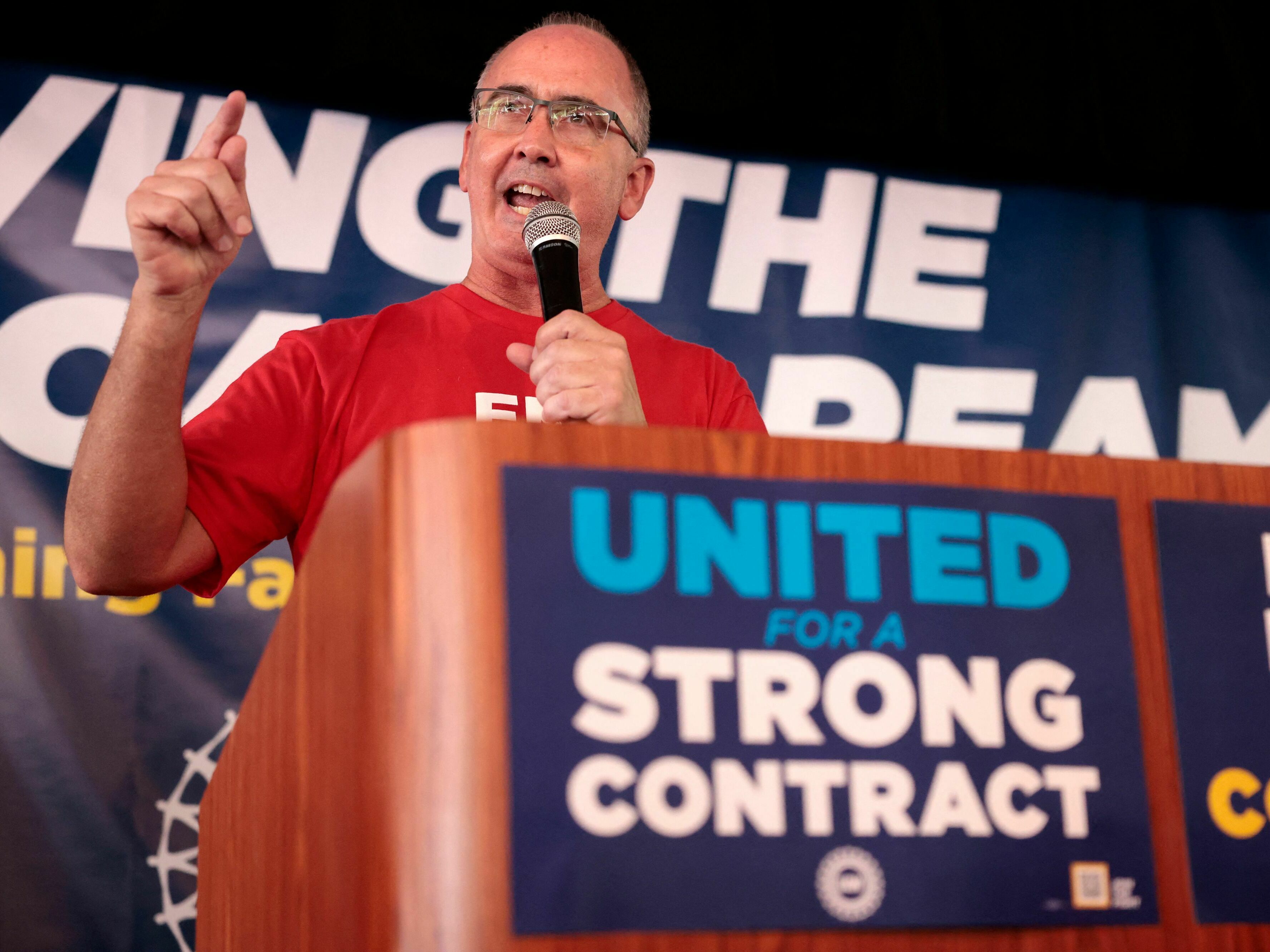 caption: UAW President Shawn Fain speaks as UAW members and their supporters gather for Solidarity Sunday at the UAW Region 1 office in Warren, Mich., on Aug. 20. The UAW has started an unprecedented strike against all three big automakers.