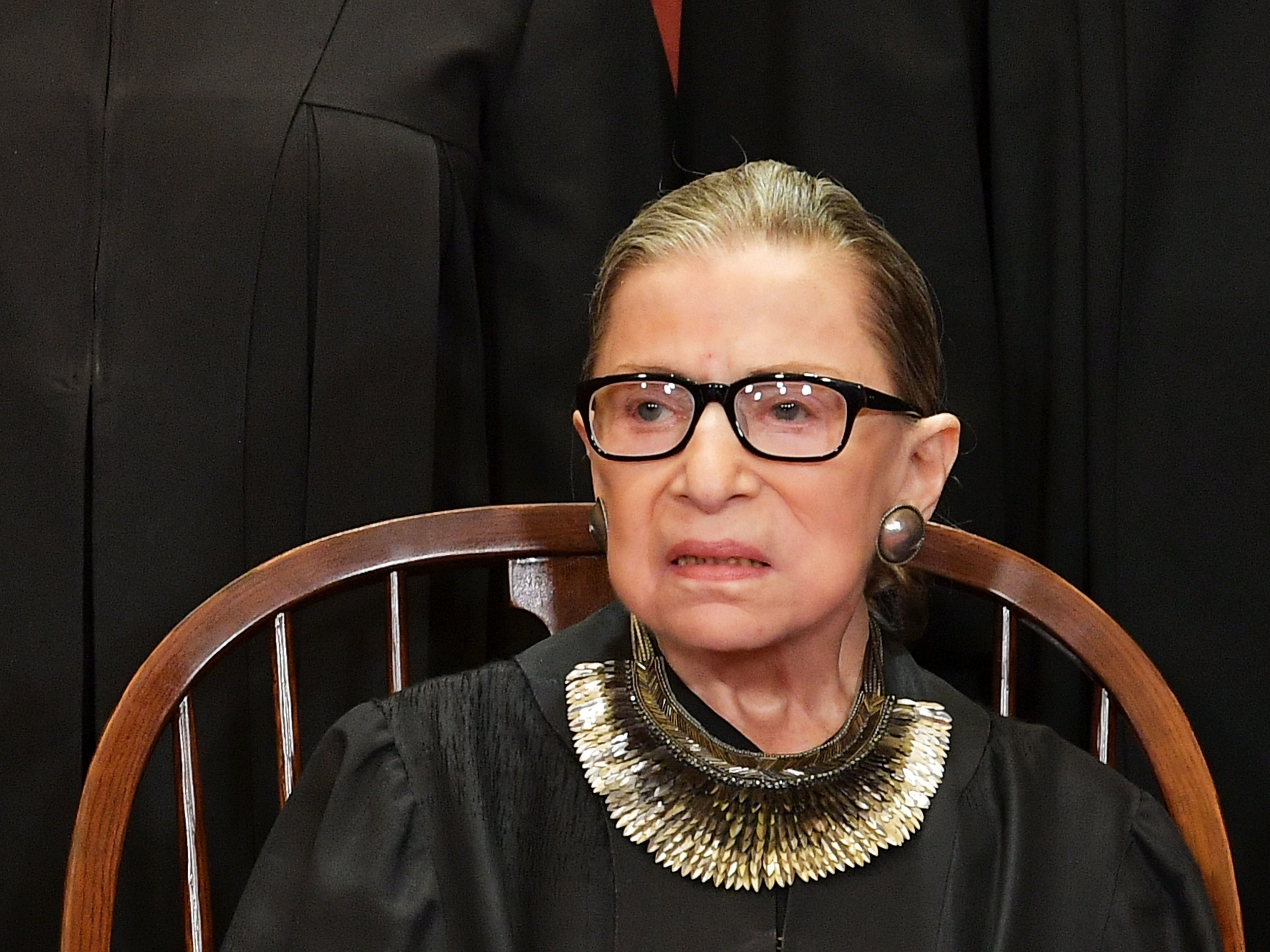 caption: Associate Justice Ruth Bader Ginsburg poses for the official photo at the Supreme Court in Washington, DC on November 30, 2018.