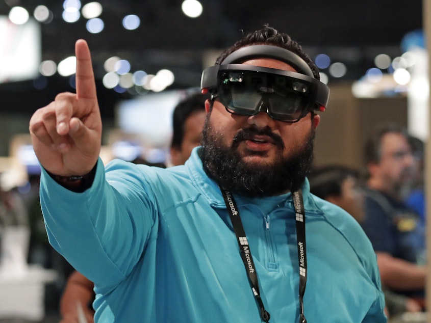 caption: Raman Ghuman demonstrates a HoloLens device at the company's annual conference for software developers, May 7, 2018, in Seattle. Microsoft workers are protesting the use of the HoloLens technology in a U.S. Amy contract.