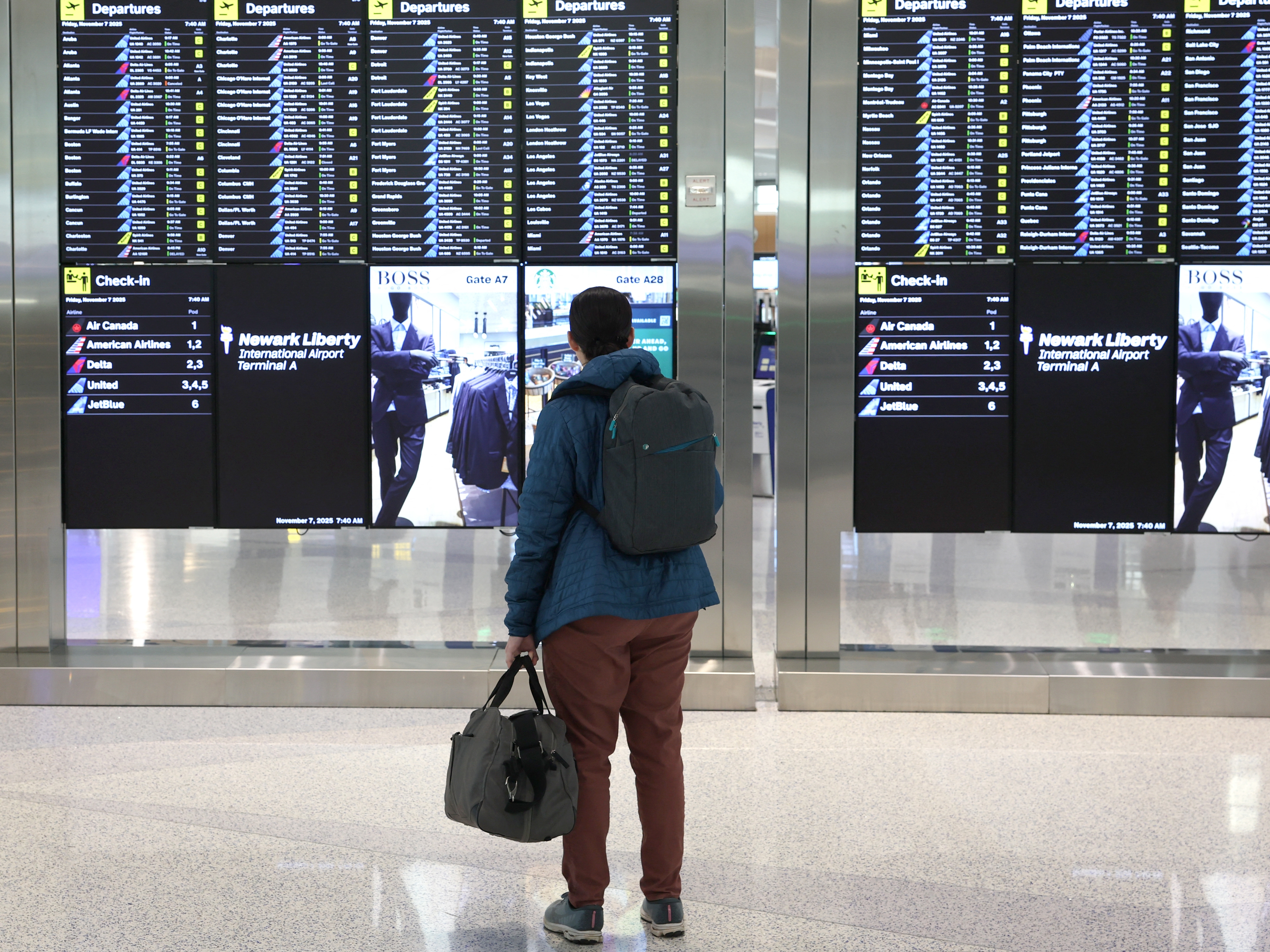 caption: A man looks at the departures board at Newark Liberty International Airport in New Jersey on Friday, the first day of FAA-mandated flight reductions.