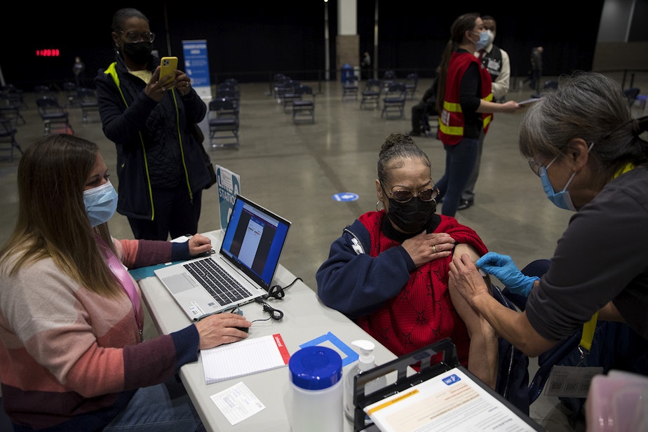 caption: Susan Hughes receives a Covid-19 vaccine at the new civilian-led mass Covid-19 vaccination site on Saturday, March 13, 2021, at Lumen Field Event Center in Seattle. 