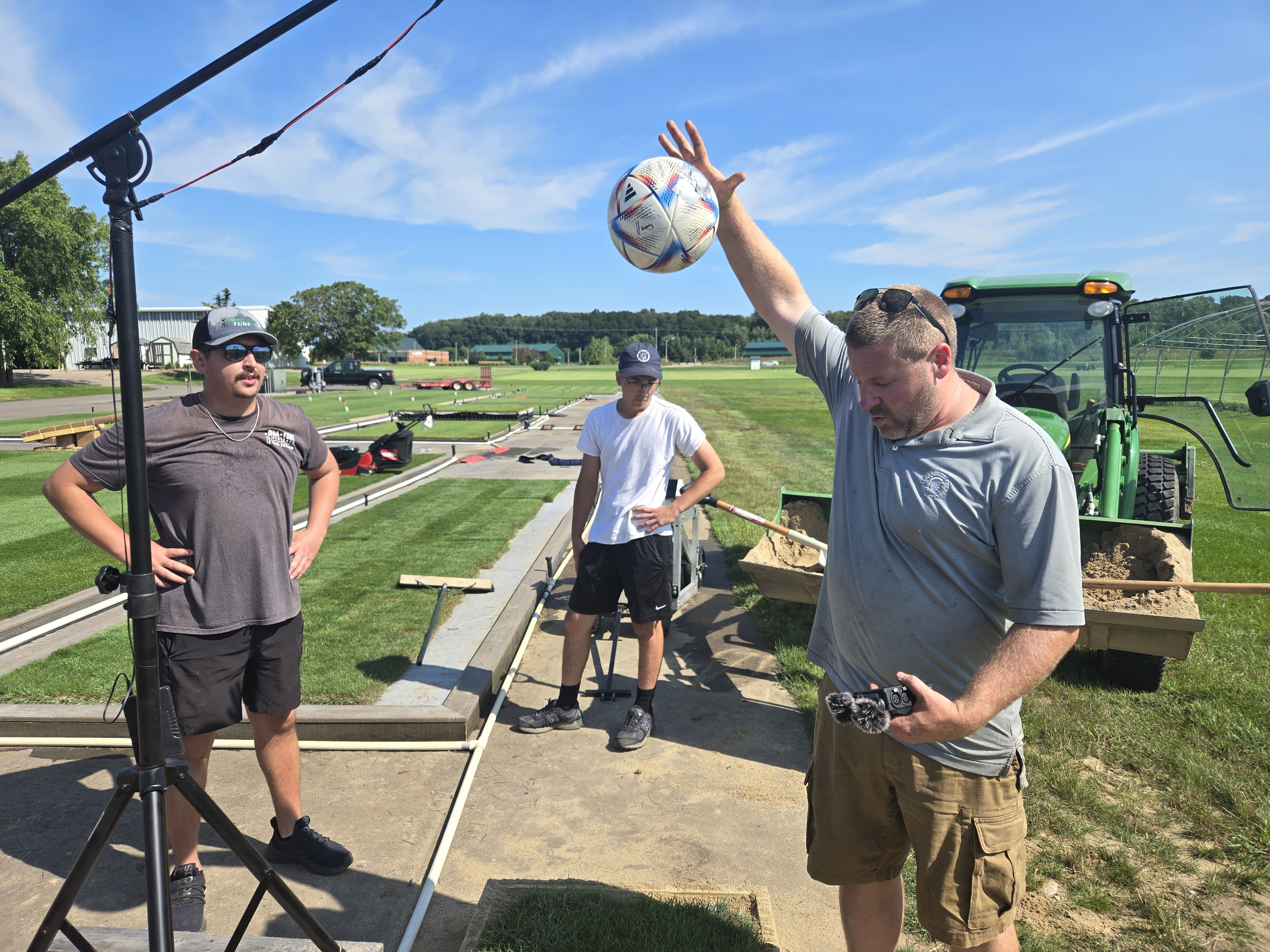 caption: Michigan State University lead research associate Ryan Bearss and students drop soccer balls on several experimental patches of turf to determine whether their bounce meets regulation height.