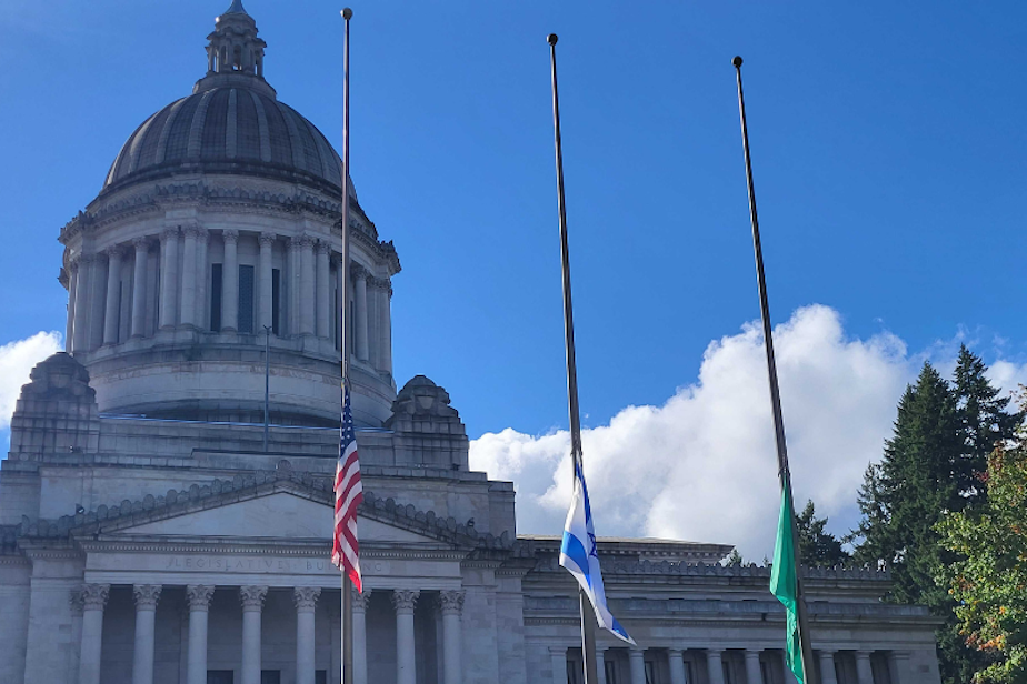 caption: The Israeli flag flies at half staff next to the U.S. flag and Washington state flag at the state Capitol in Olympia, Oct. 12, 2023. Gov. Jay Inslee ordered the flag to be raised in the week after Hamas attacked Israel.