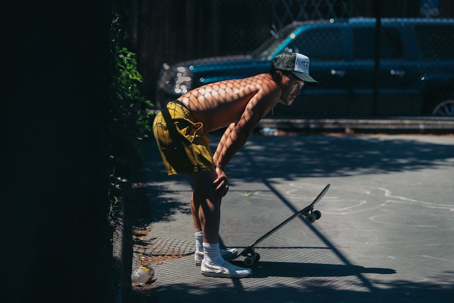 caption: Tony Nguyen takes a break from skateboarding in 100-degree heat on Sunday, June 27, 2021, at Cal Anderson Park on Capitol Hill. 