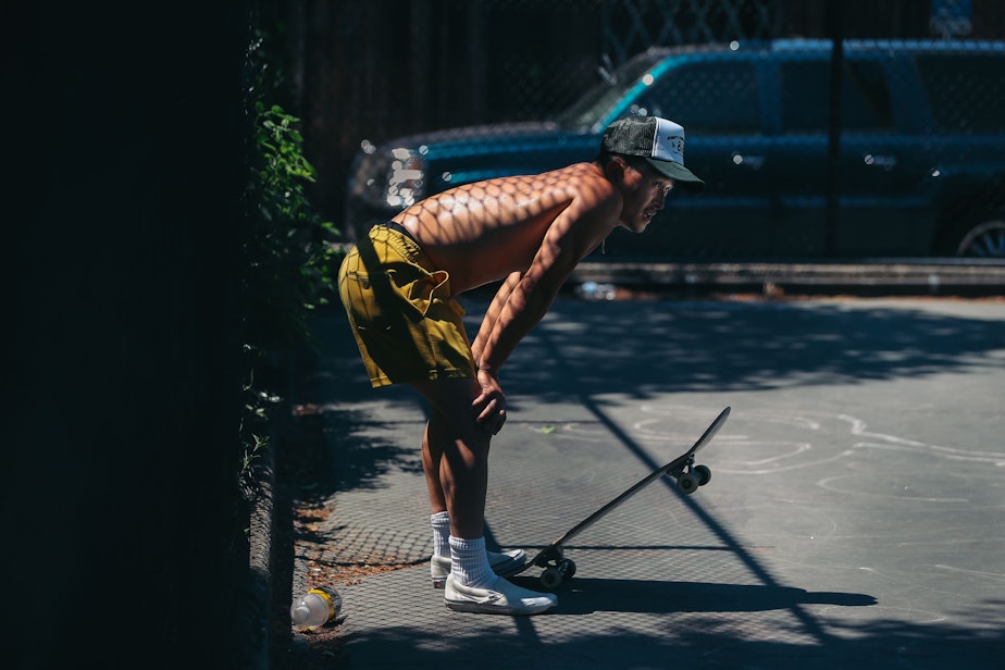 caption: Tony Nguyen takes a break from skateboarding in 100-degree heat on Sunday, June 27, 2021, at Cal Anderson Park on Capitol Hill.