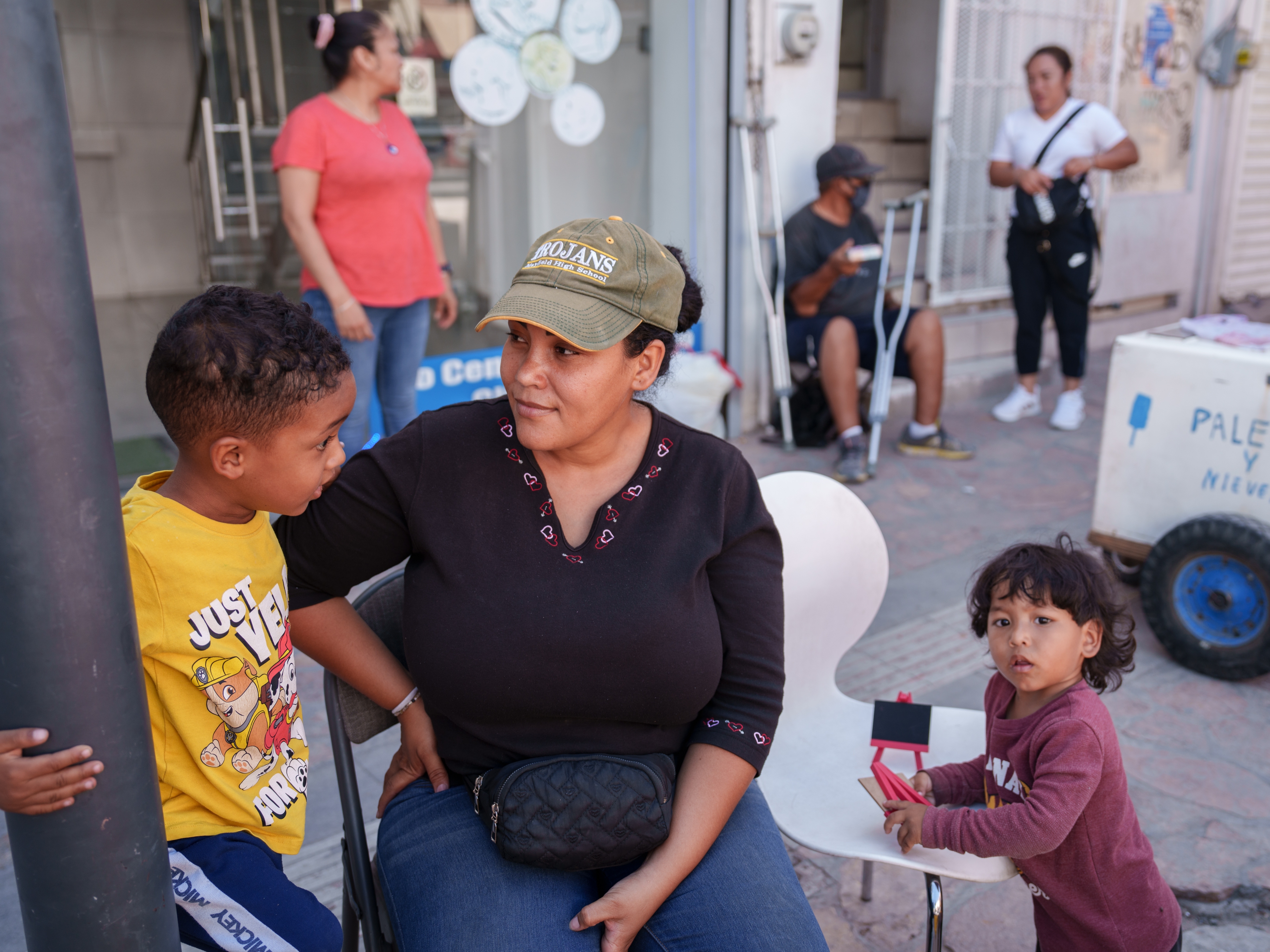 caption: Yasmelin Velazquez, 35, from Venezuela sits with her sons (from left) Jordan and Jeremias Velazquez while selling souvenirs in Ciudad Juárez, Chihuahua state, Mexico, on Saturday. Velazquez is part of a growing number of migrants staying in Juárez and working while trying to get an appointment via the CBP One app.   