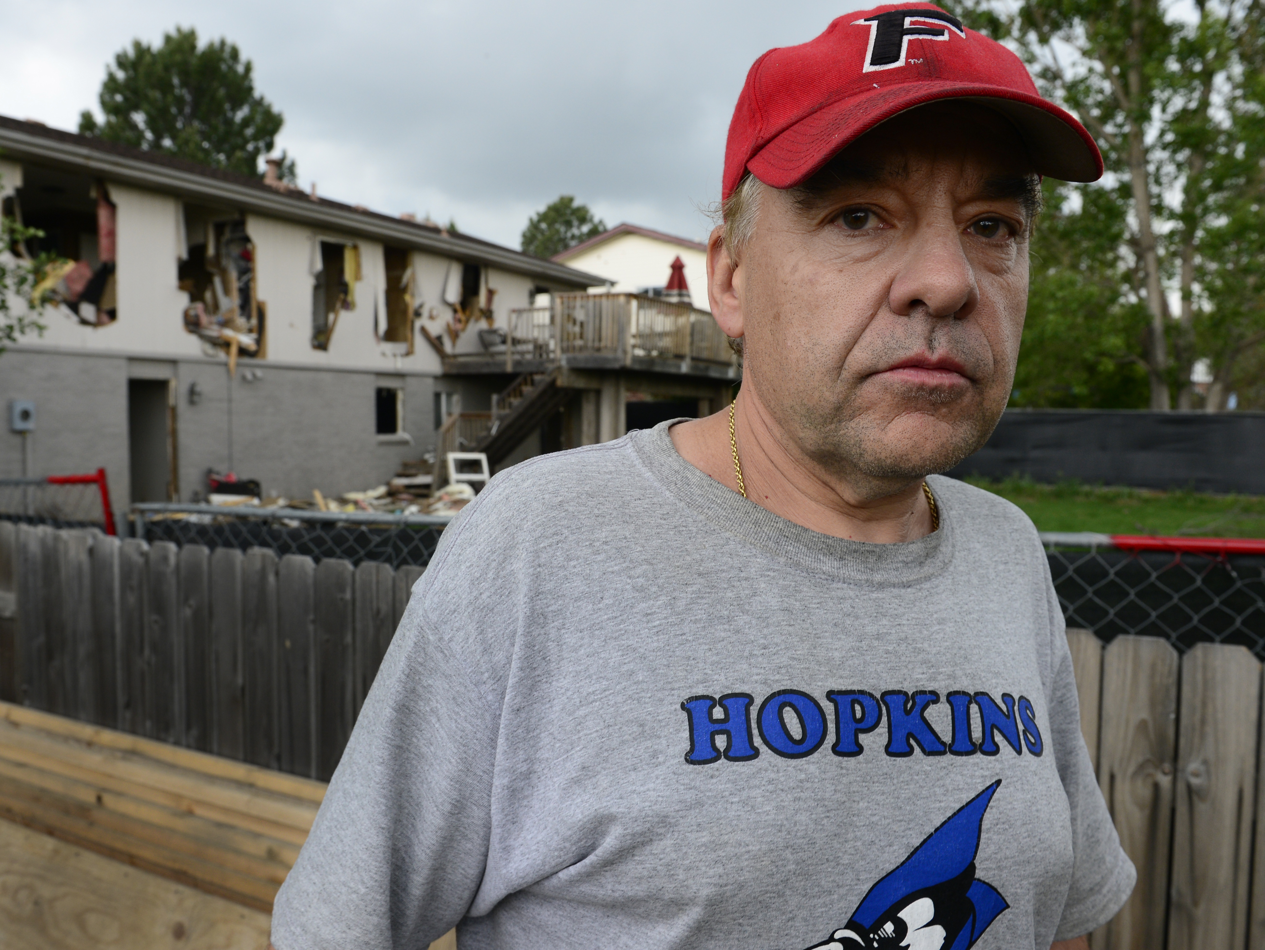 caption: Leo Lech stands on a pile of wood in his neighbor's yard, which overlooks the back of his home in Greenwood Village, Colo. The home was destroyed by the police, and on Tuesday, a federal appeals court ruled that the city does not owe Lech any compensation.