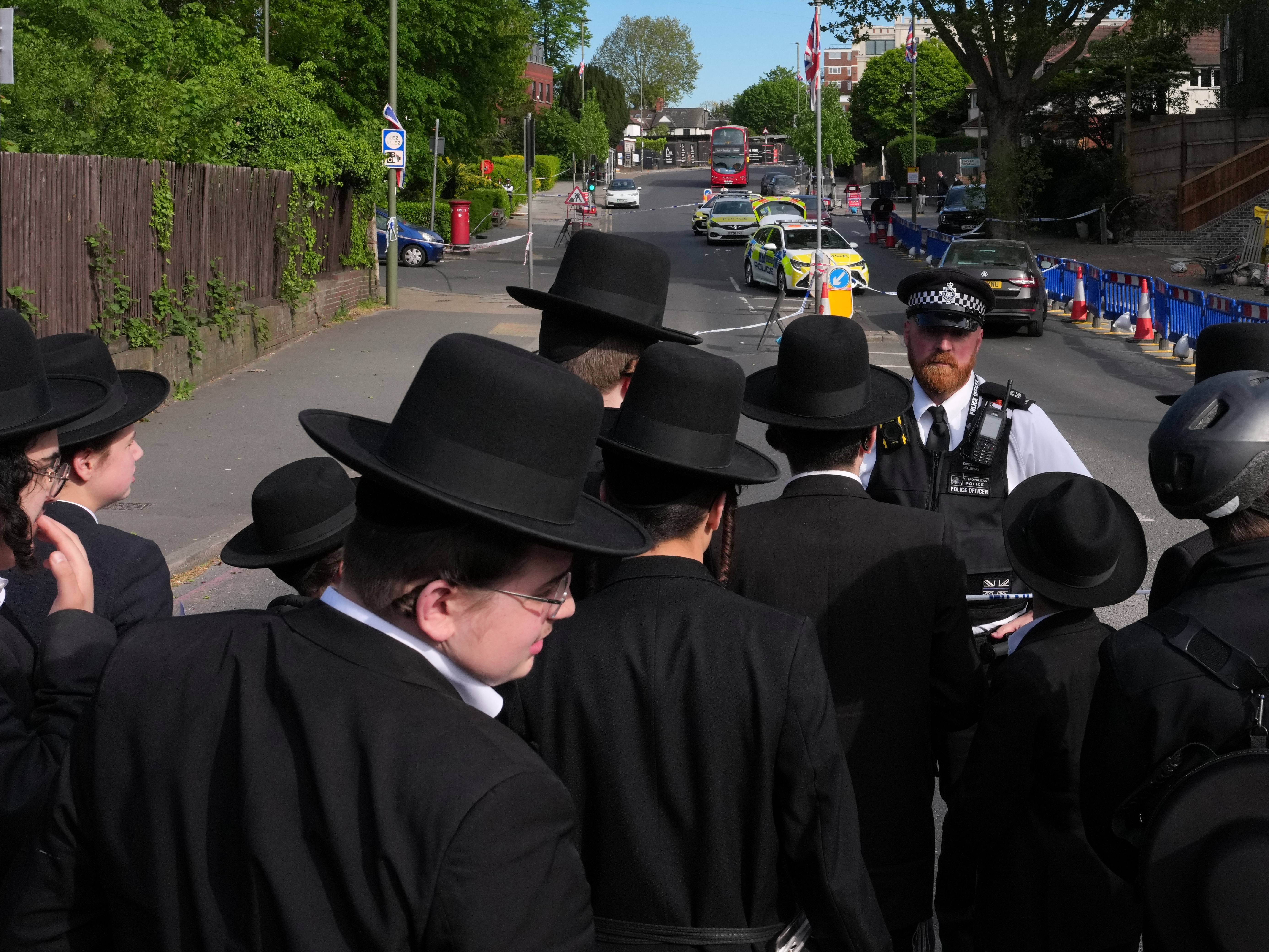 caption: Members of the community watch as forensic officers search the area after two people were stabbed in the Golders Green neighborhood, that has a large Jewish community, in London, Wednesday.