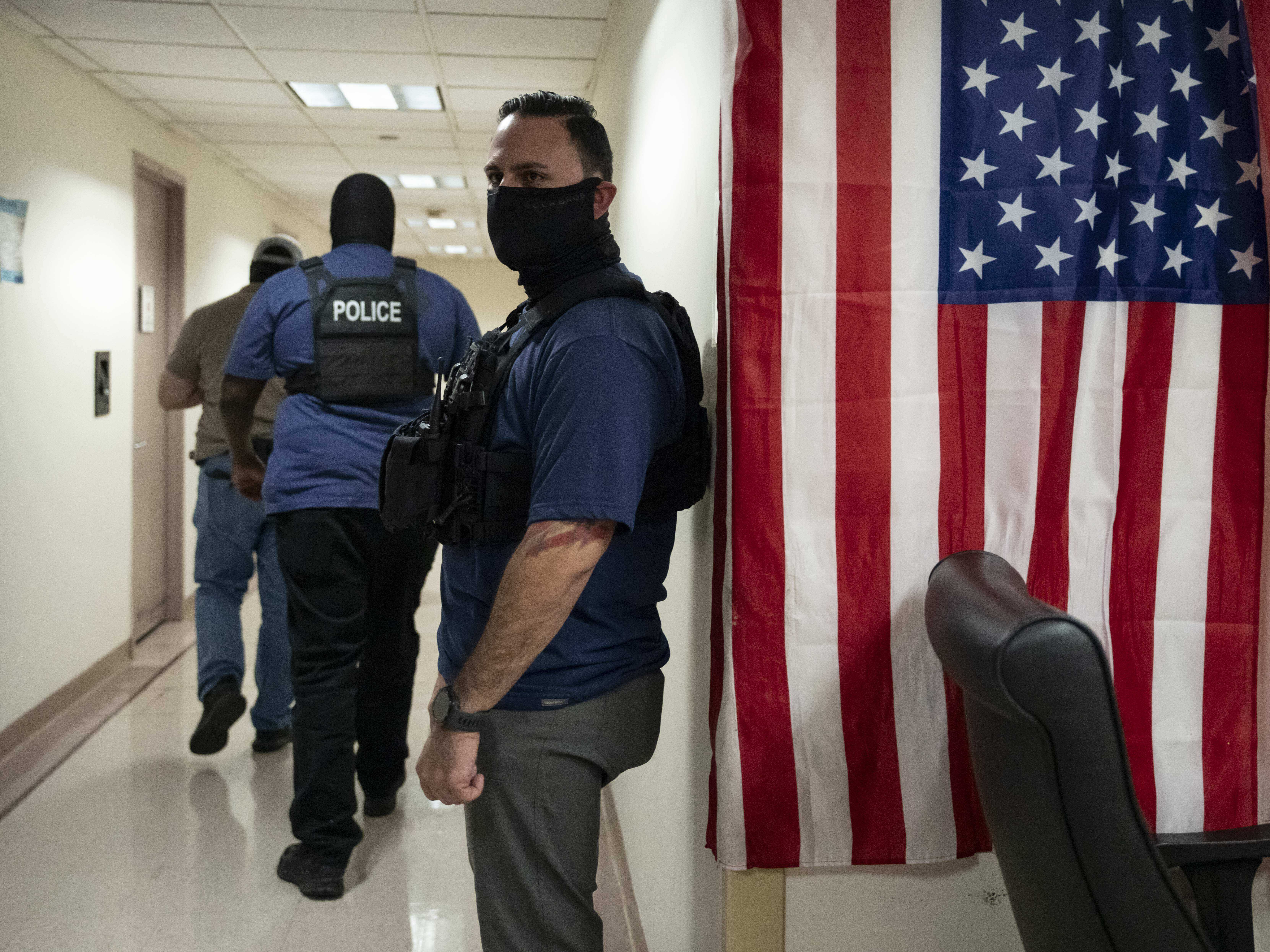 caption: Federal agents stand outside an immigration court at the Jacob K. Javits federal building in New York in September 2025.
