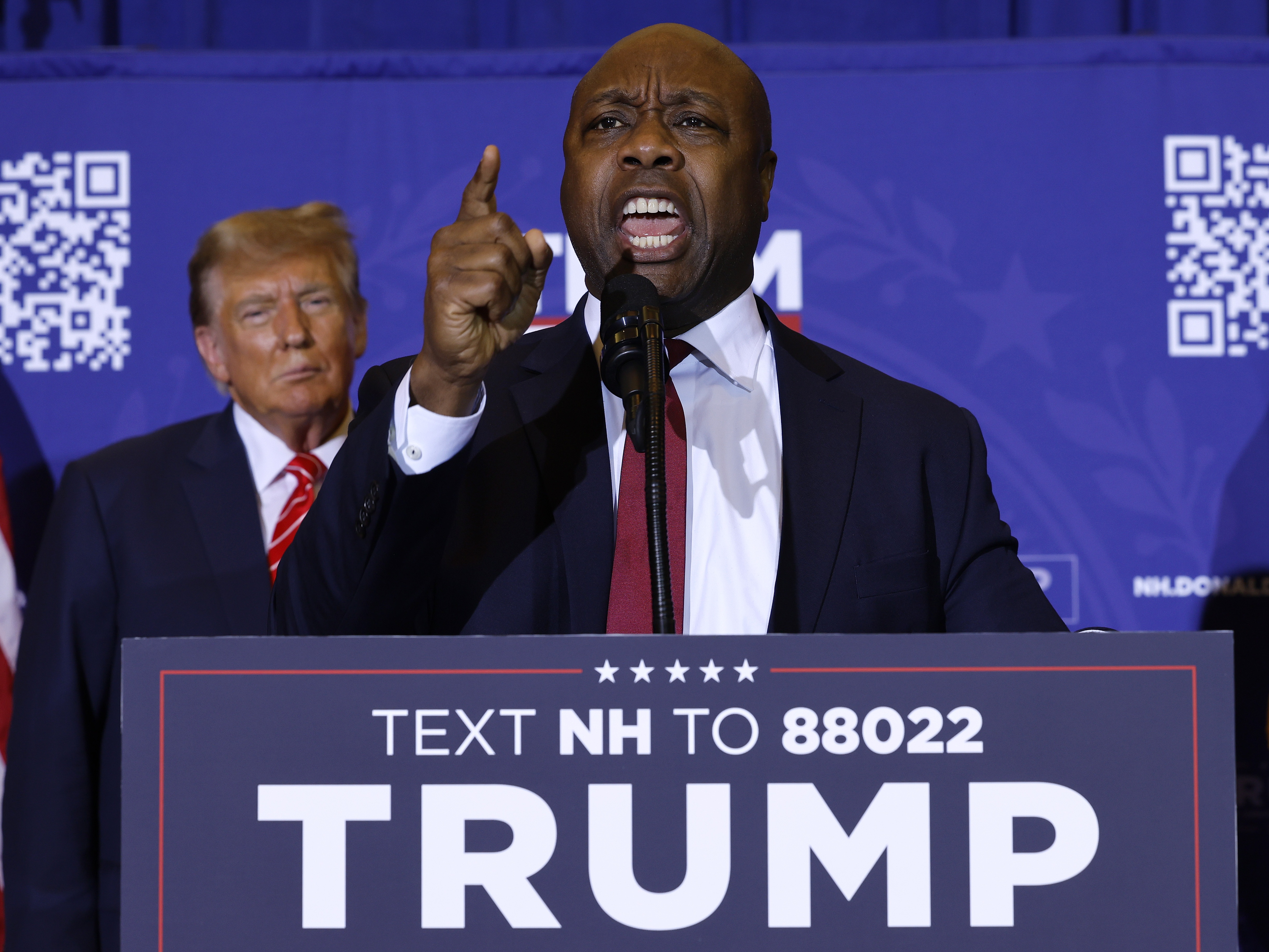 caption: Sen. Tim Scott (R-SC) speaks as Republican presidential candidate and former President Donald Trump looks on during a campaign rally on January 19 in Concord, N.H.