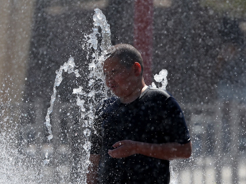 caption: A boy plays in a splash pad at Riverview Park on June 5 in Mesa, Ariz.