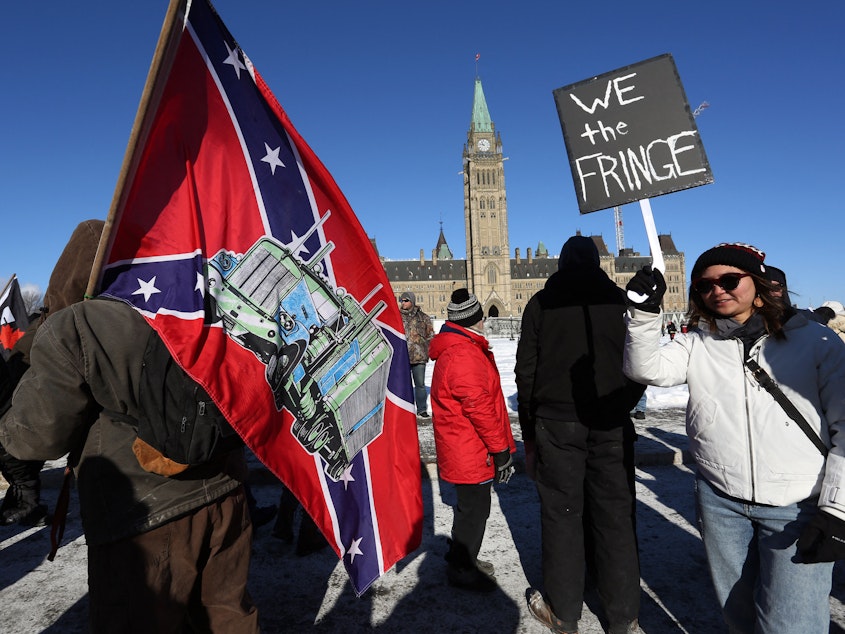 caption: A man carries a Confederate flag during the protests in Ottawa in January. Along with Canadian flags, signs and flags with extremist views have been seen at the demonstrations.