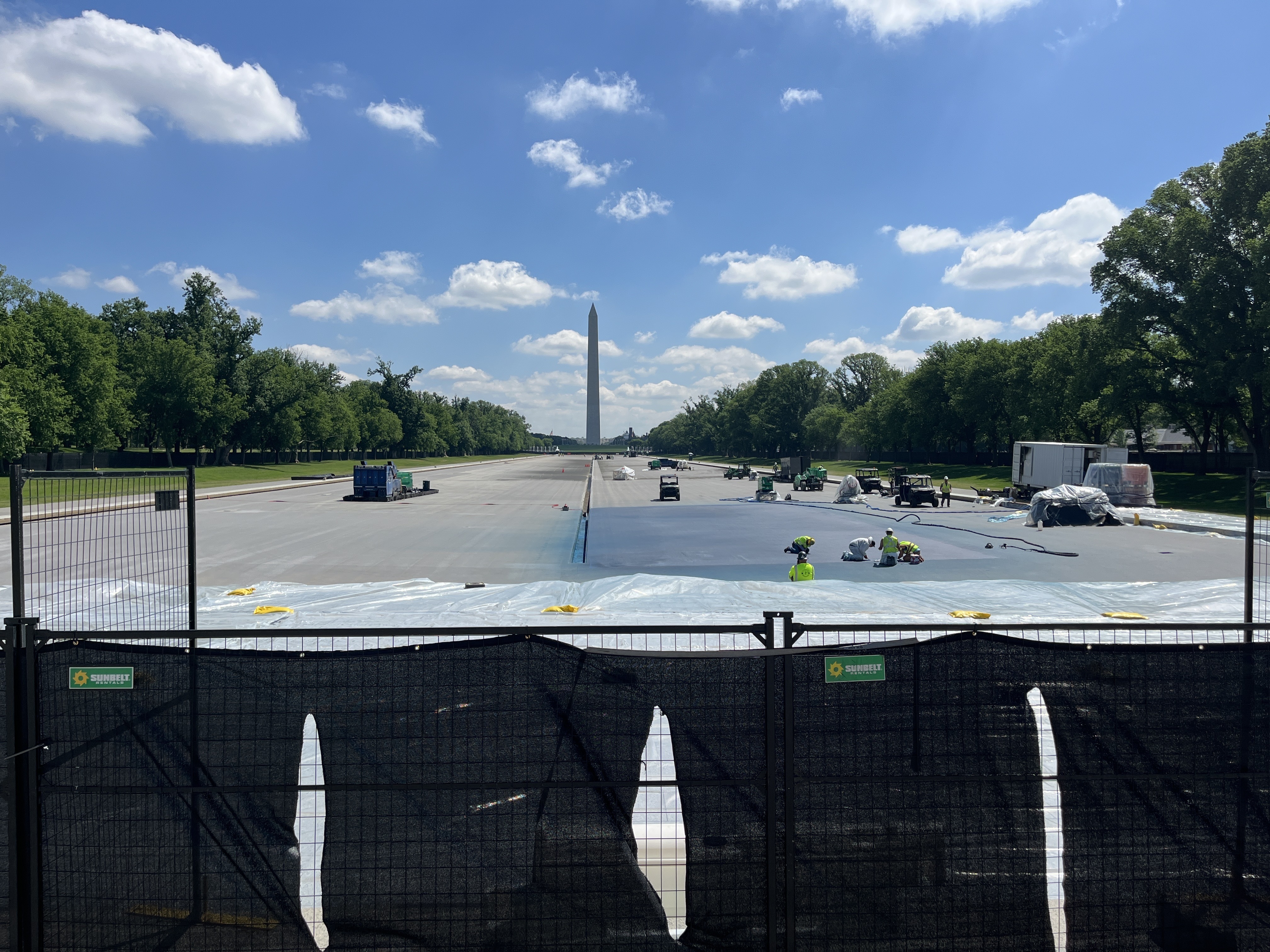 caption: Workers paint a corner of the reflecting pool blue on Monday morning.
