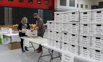 caption: Poll workers Angela and Zach Achten check-in a box of absentee ballots in the gym at Sun Prairie High School on November 3, 2020 in Sun Prairie, Wisconsin. (Andy Manis/Getty Images)