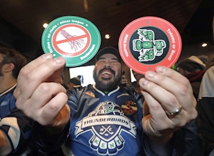 caption: Otto Rogers playfully holds up stickers against the proposed name Kraken and in support of Totems following the announcement of a new NHL hockey team in Seattle, at a celebratory party Tuesday, Dec. 4, 2018, in Seattle. 