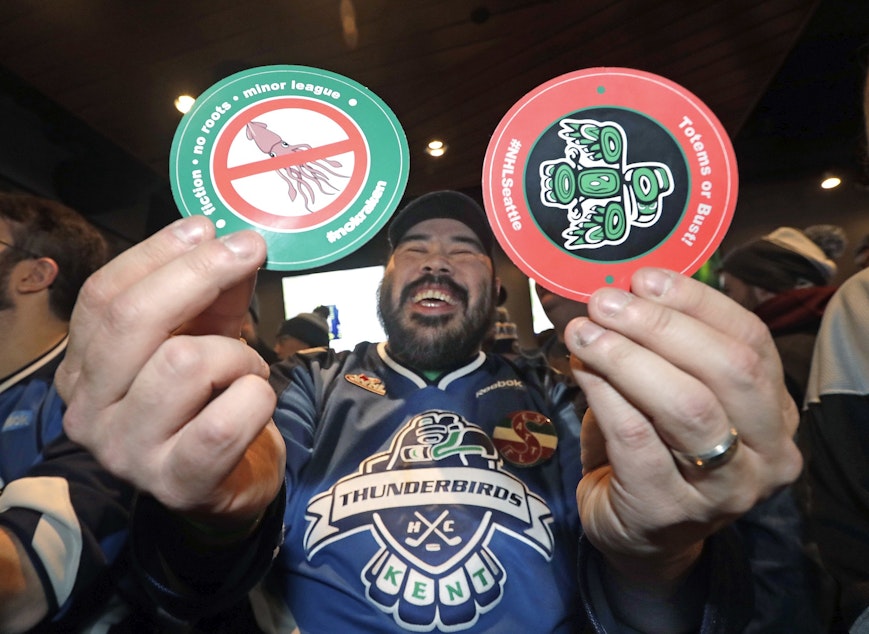 caption: Otto Rogers playfully holds up stickers against the proposed name Kraken and in support of Totems following the announcement of a new NHL hockey team in Seattle, at a celebratory party Tuesday, Dec. 4, 2018, in Seattle. 