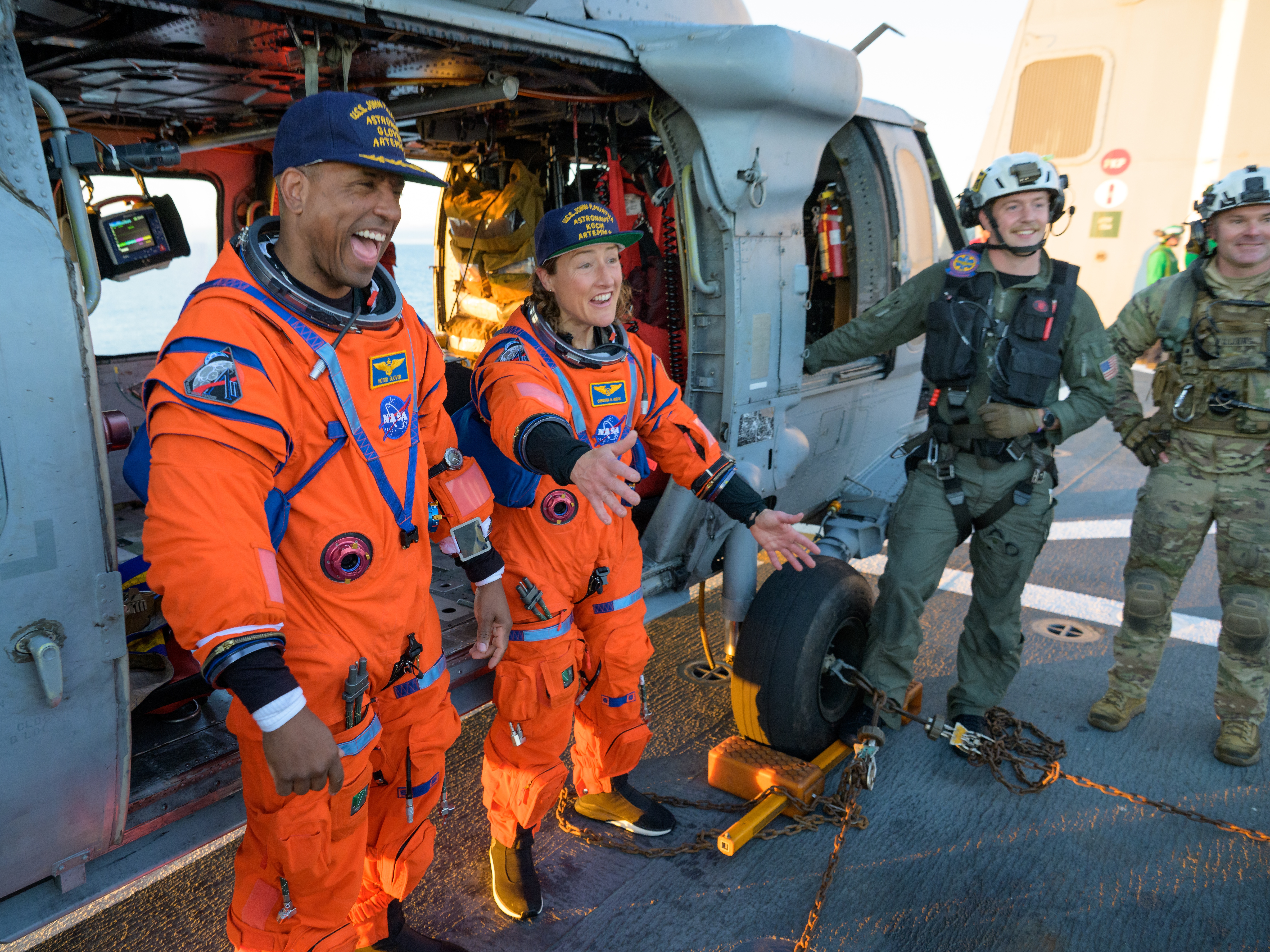 caption: NASA astronaut Victor Glover, Artemis II pilot, left, and NASA astronaut Christina Koch, Artemis II mission specialist are seen sitting on a Navy MH-60 Seahawk from Helicopter Sea Combat Squadron (HSC) 23 on the flight deck of USS John P. Murtha.