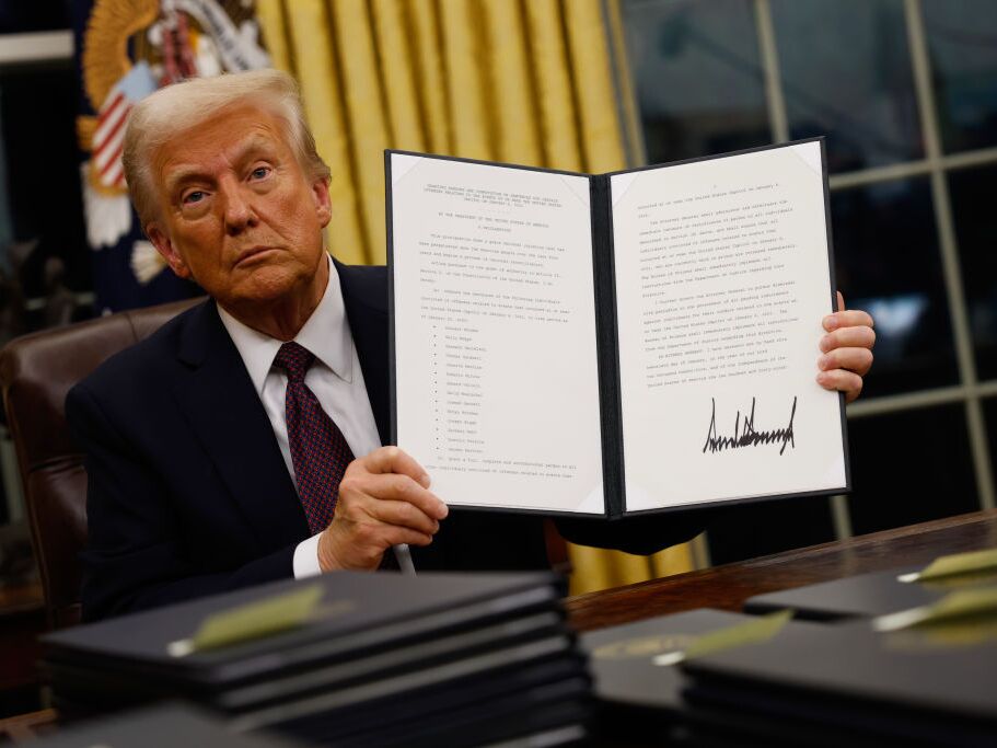 caption: President Trump signs executive orders in the Oval Office on Jan. 20.