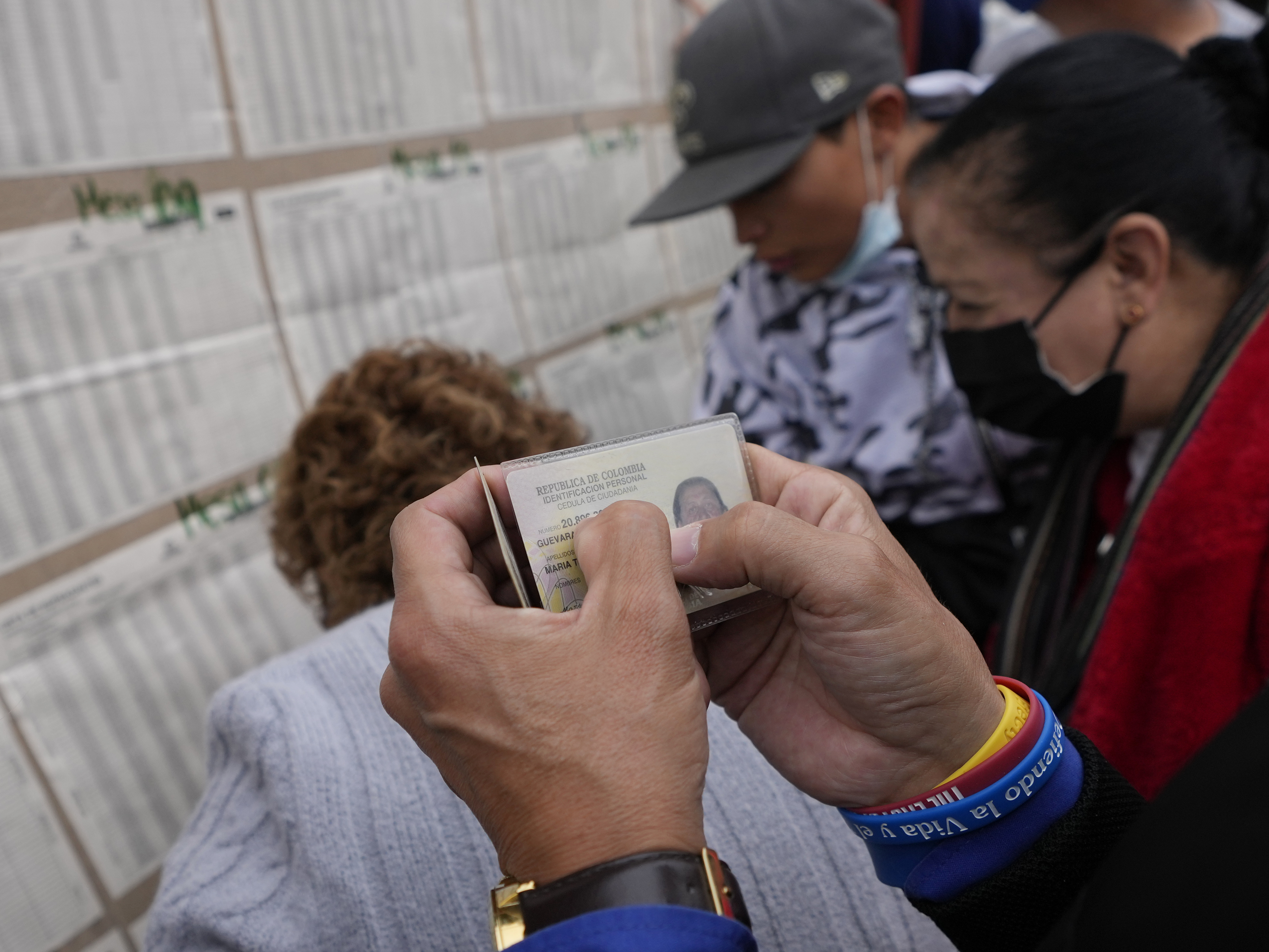 caption: People check a voter list to confirm where they should cast their ballots during legislative elections in Bogota, Colombia, on Sunday.