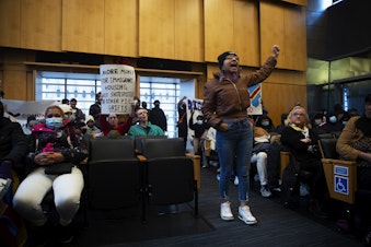 caption: Rosario Lopez leads a chant in council chambers following public comment after asylum seekers, activists and allies marched to Seattle City Hall to ask for assistance with housing on Tuesday, February 27, 2024, in Seattle. Seattle city council members abruptly left council chambers. 