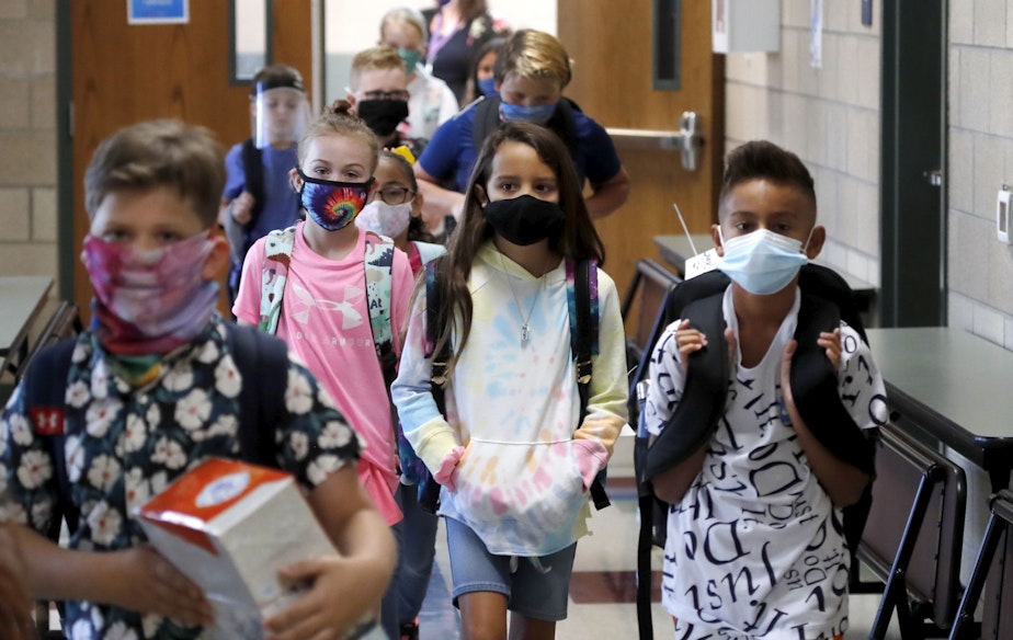 caption: Wearing masks to prevent the spread of COVID19, elementary school students walk to classes to begin their school day in Godley, Texas. (LM Otero/AP)