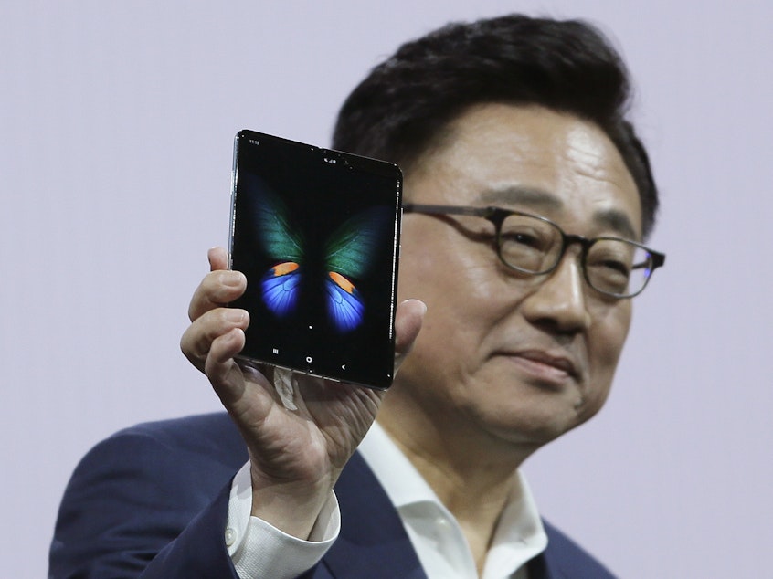 caption: Samsung executive DJ Koh holds up the new Galaxy Fold smartphone during an event on Feb. 20 in San Francisco. On Monday, the company announced it is delaying the device's launch.
