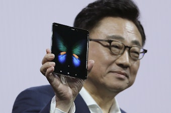 caption: Samsung executive DJ Koh holds up the new Galaxy Fold smartphone during an event on Feb. 20 in San Francisco. On Monday, the company announced it is delaying the device's launch.
