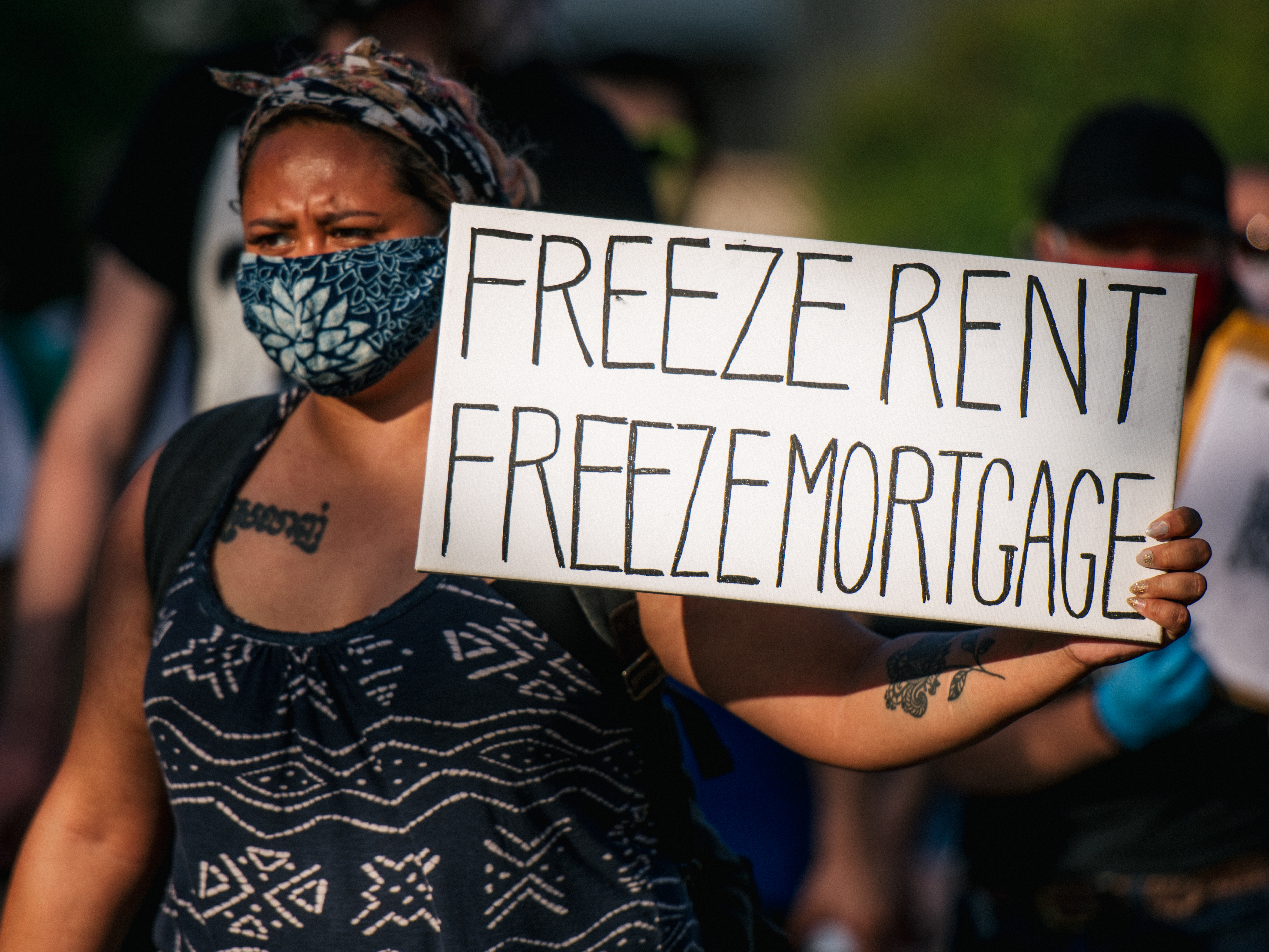 caption: A woman joins with other demonstrators during the "Cancel Rent and Mortgages" rally in late June in Minneapolis. The march was demanding the temporary cancellation of rents and mortgages as COVID-19 batters the economy.