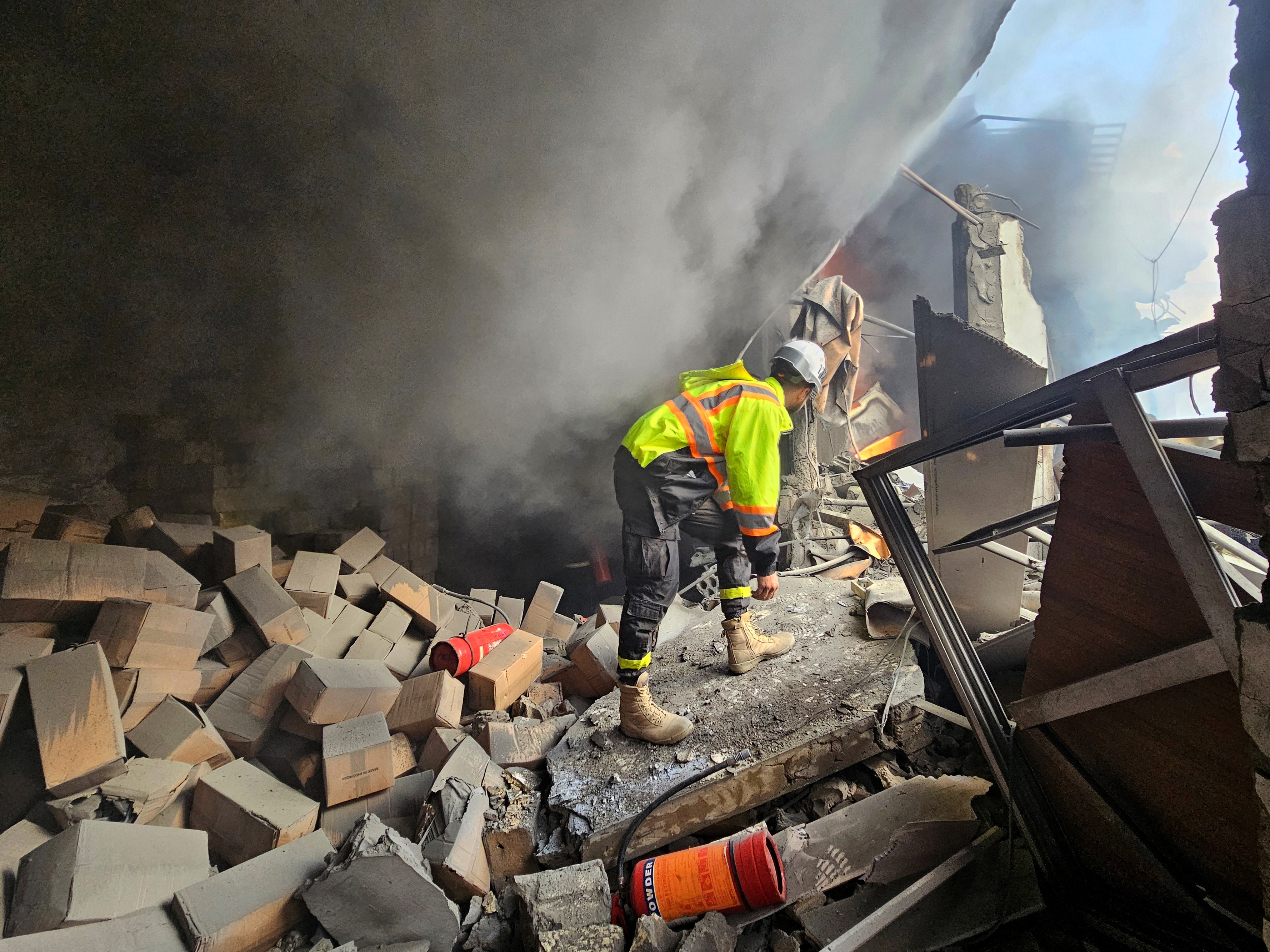 caption: A first responder looks for survivors at the scene of an Israeli airstrike that targeted a building in a southern suburb of Beirut on Tuesday.
