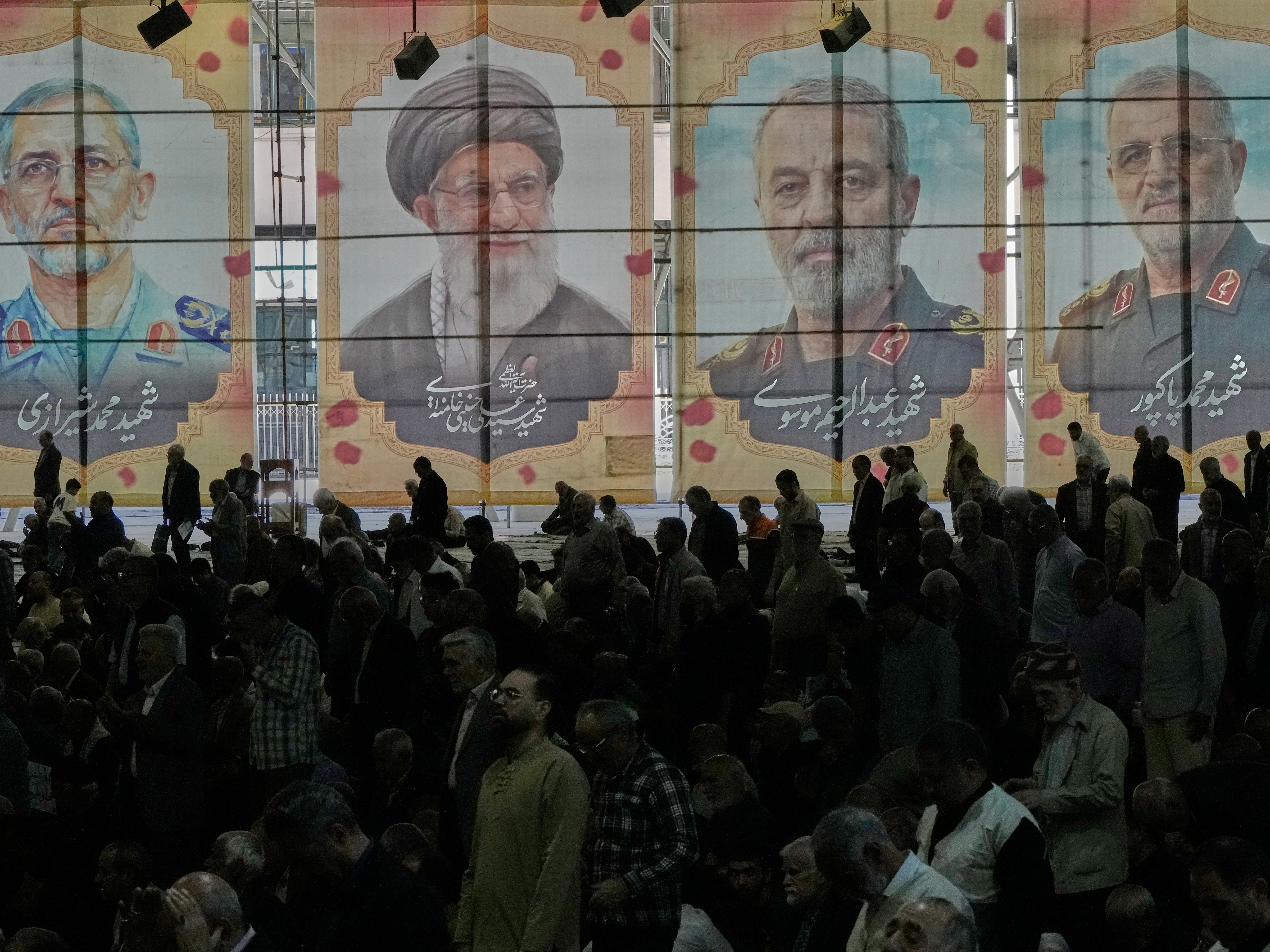 caption: Iranian worshippers perform their Friday prayers under the portraits of the late Iranian Supreme Leader Ayatollah Ali Khamenei (second left) and top military officials who were killed during the U.S.-Israel campaign, at the Tehran University campus, in Tehran, Iran, on April 24.