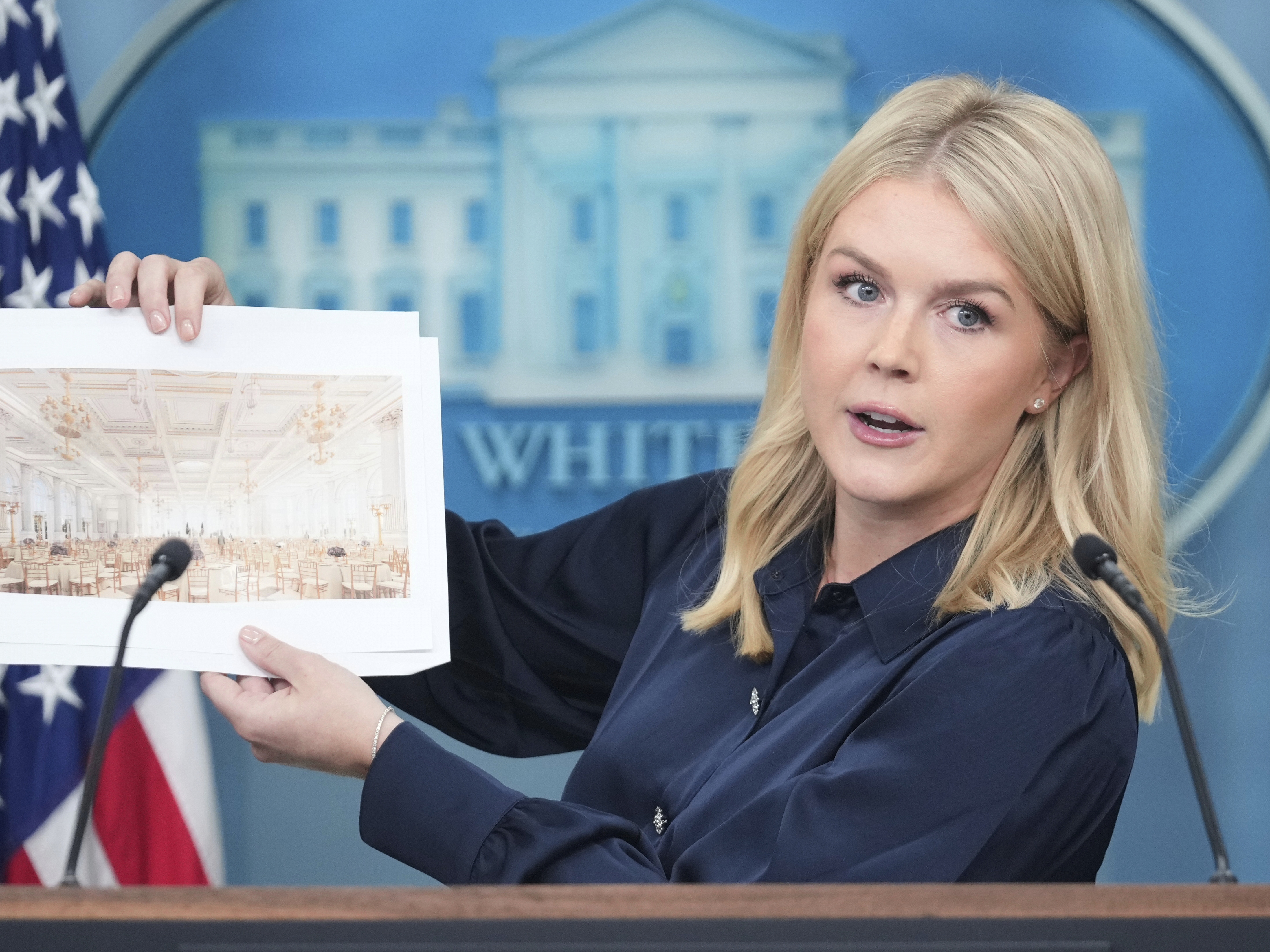 caption: White House press secretary Karoline Leavitt holds up photos of the planned new White House ballroom during a press briefing at the White House on July 31. According to the White House, the new White House ballroom will be approximately 90,000 square feet and cost about $200 million.