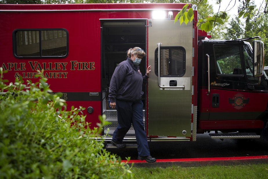 caption: Puget Sound Regional Firefighter Nikki Smith exits a fire truck after administering a Moderna Covid-19 vaccine for a homebound individual on Monday, May 24, 2021, in Kent. 