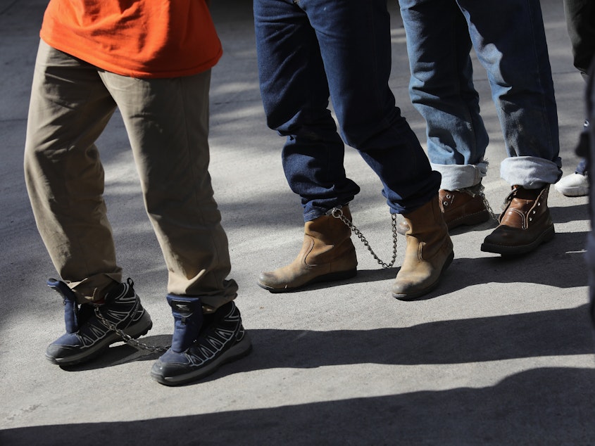 caption: Unauthorized immigrants leave a court in shackles in McAllen, Texas. More than 40,000 immigration court hearings have been canceled since the government shut down.