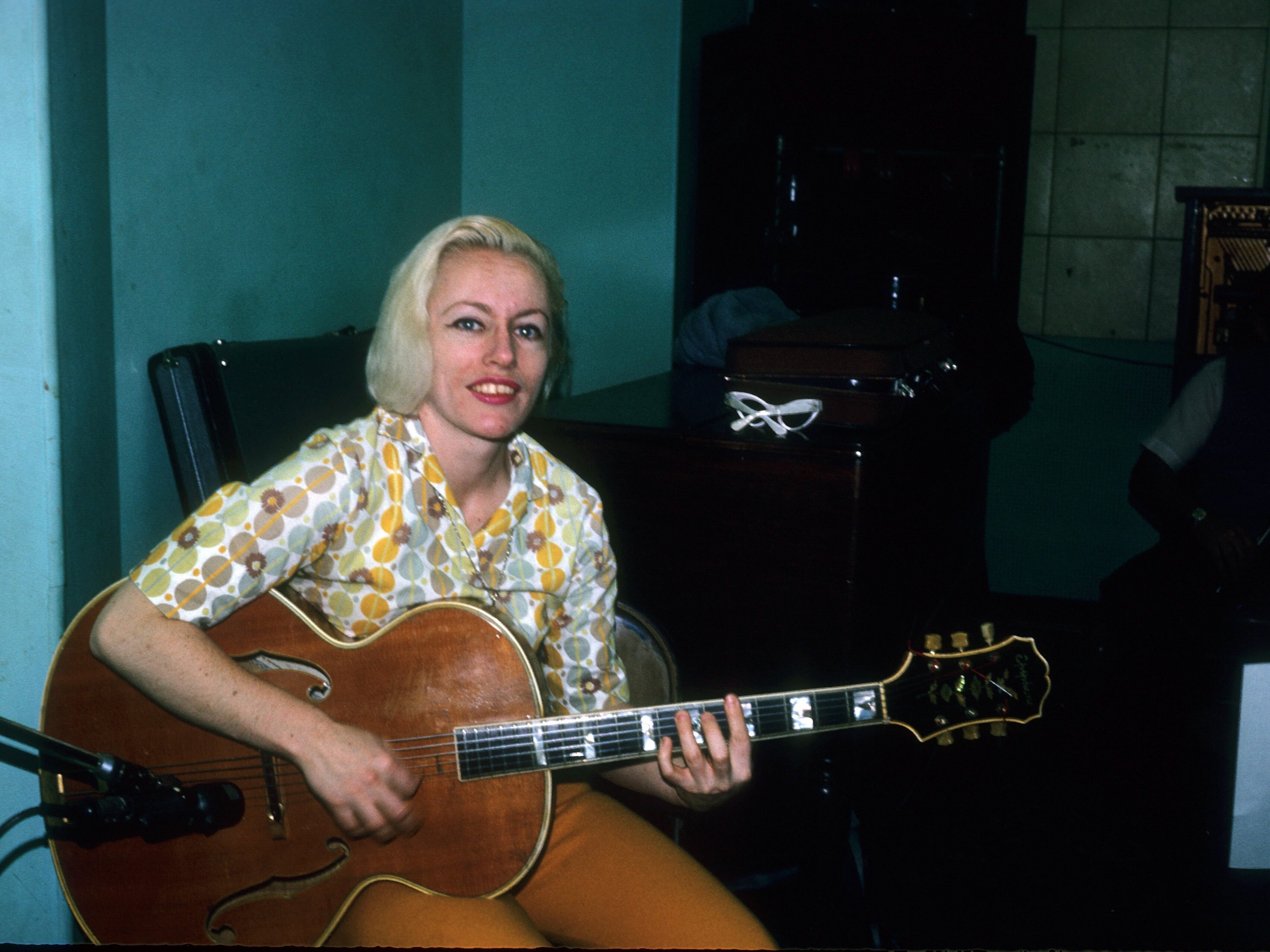 caption: Bassist Carol Kaye plays an Epiphone hollowbody electric guitar in April 1966 in Los Angeles, California.