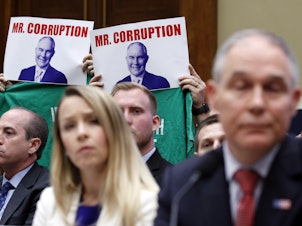 caption: Protesters hold up signs and shirts behind then-Environmental Protection Agency Administrator Scott Pruitt while testifying on Capitol Hill in April. Pruitt was one of a handful of Trump administration officials forced to resign while facing ethics investigations this year.