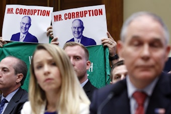 caption: Protesters hold up signs and shirts behind then-Environmental Protection Agency Administrator Scott Pruitt while testifying on Capitol Hill in April. Pruitt was one of a handful of Trump administration officials forced to resign while facing ethics investigations this year.
