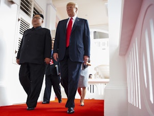 caption: North Korea's leader Kim Jong Un and President Trump walk together at a resort on Sentosa Island in Singapore on June 12, 2018.