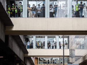 caption: Bystanders watch from footbridges Wednesday as riot police stand guard below outside a building in Hong Kong.
