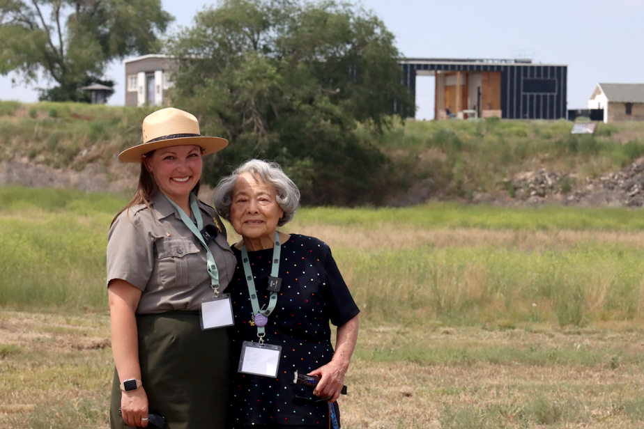 caption: Kelsea Larsen (left) with her grandmother, Fujiko Gardner (right),  a survivor of Minidoka prison camp in rural Idaho. In the distance is the visitor's center with a museum about the camps.