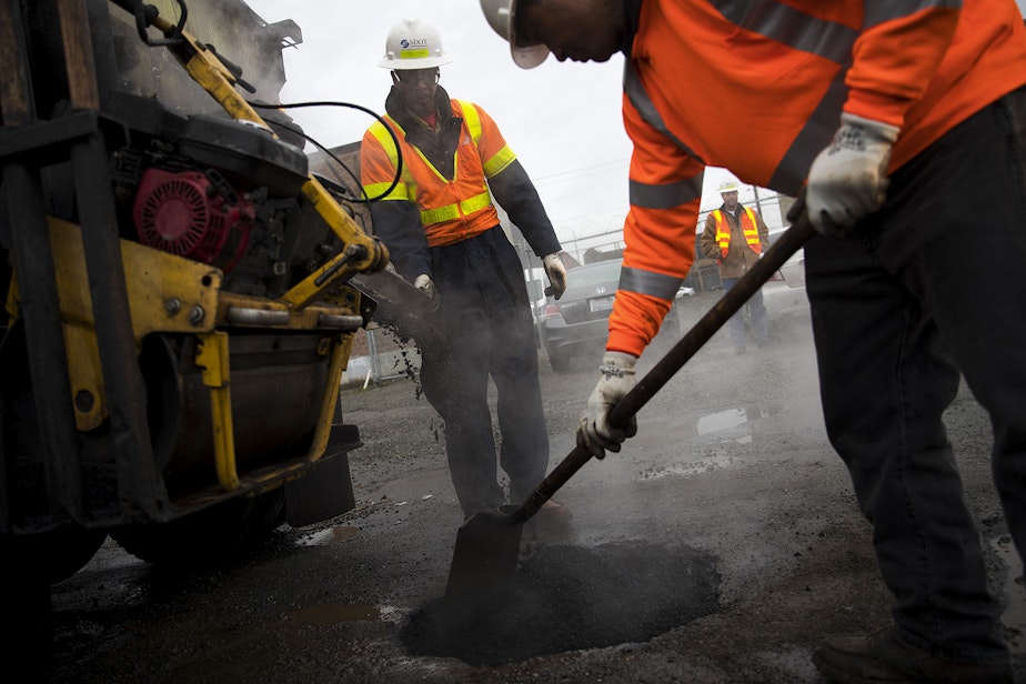 caption: Seattle Department of Transportation employees Ben Darrett, left, and Koli Makasini, right, fill a pothole on Tuesday, January 8, 2019, at the intersection of South Forest Street and Occidental Avenue South in Seattle. 