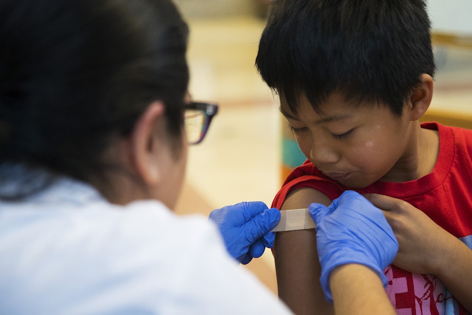 caption: Erika Sandoval, a nurse with the Seattle Visiting Nurse Association, gives first-grade student Tavita Tuilagi-Su a bandaid after administering a flu shot on Tuesday, October 22, 2019, at Concord International Elementary School in Seattle.