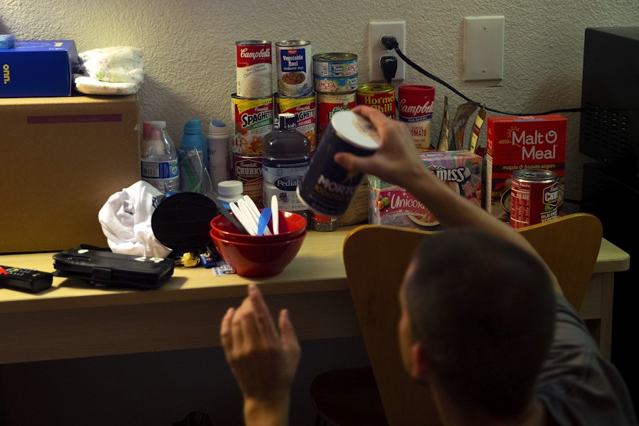 caption: Sean stocks a counter of the family's motel room with food for the week on Friday, August 26, 2022.