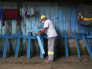 caption: Ulisses Xavier, 52, who has worked for 16 years at Nossa Senhora cemetery in Manaus, Brazil, makes wooden crosses to supplement his income. The cemetery has seen a surge in the number of new graves after the outbreak of COVID-19.