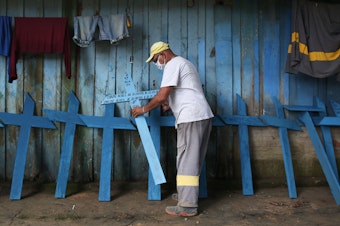 caption: Ulisses Xavier, 52, who has worked for 16 years at Nossa Senhora cemetery in Manaus, Brazil, makes wooden crosses to supplement his income. The cemetery has seen a surge in the number of new graves after the outbreak of COVID-19.