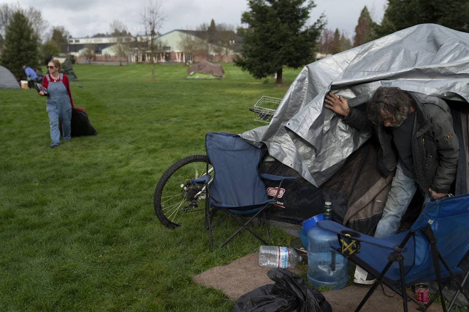 caption: Cassy Leach, left, a nurse, who leads a group of volunteers who provide food, medical care and other basic goods to the hundreds of homeless people living in the parks, carries items while helping homeless people camping in Fruitdale Park move their tents on Saturday, March 23, 2024, in Grants Pass, Oregon.