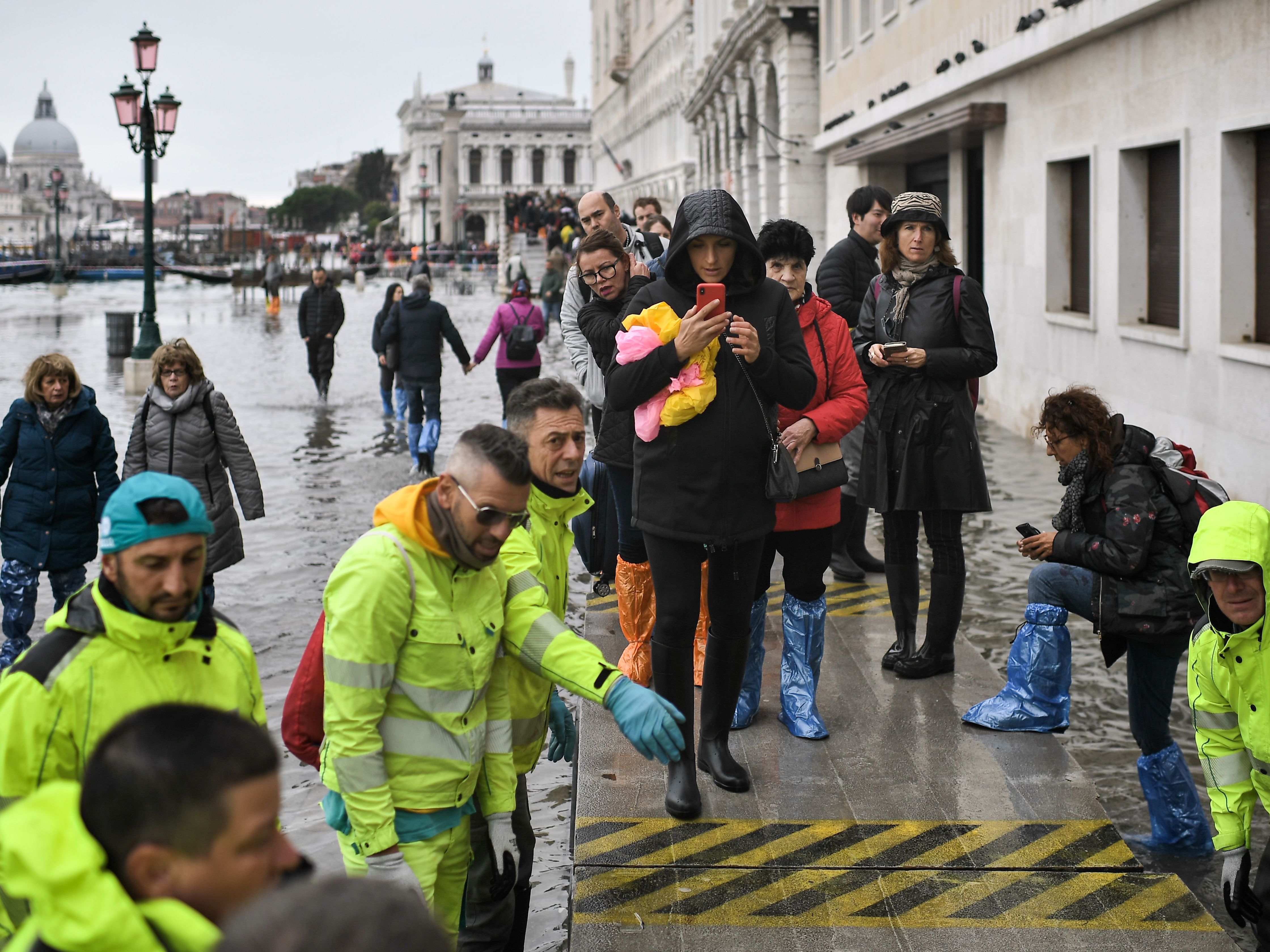 caption: Volunteers set up a footbridge across Venice's flooded Riva degli Schiavoni embankment on Nov. 13.