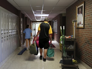 caption: Cesa Pusateri, 12, and her grandfather, Timothy Waxenfelter, principal of Quigley Catholic High School, leave with his collection of speech and debate books after the closure of the school in Baden, Pa., on June 8, 2020. According to the National Catholic Educational Association, at least 100 schools have announced in recent weeks that they won't reopen this fall.