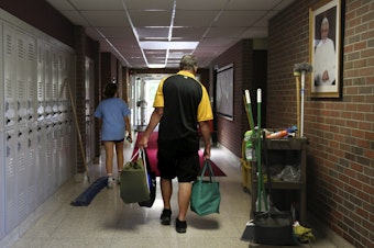 caption: Cesa Pusateri, 12, and her grandfather, Timothy Waxenfelter, principal of Quigley Catholic High School, leave with his collection of speech and debate books after the closure of the school in Baden, Pa., on June 8, 2020. According to the National Catholic Educational Association, at least 100 schools have announced in recent weeks that they won't reopen this fall.