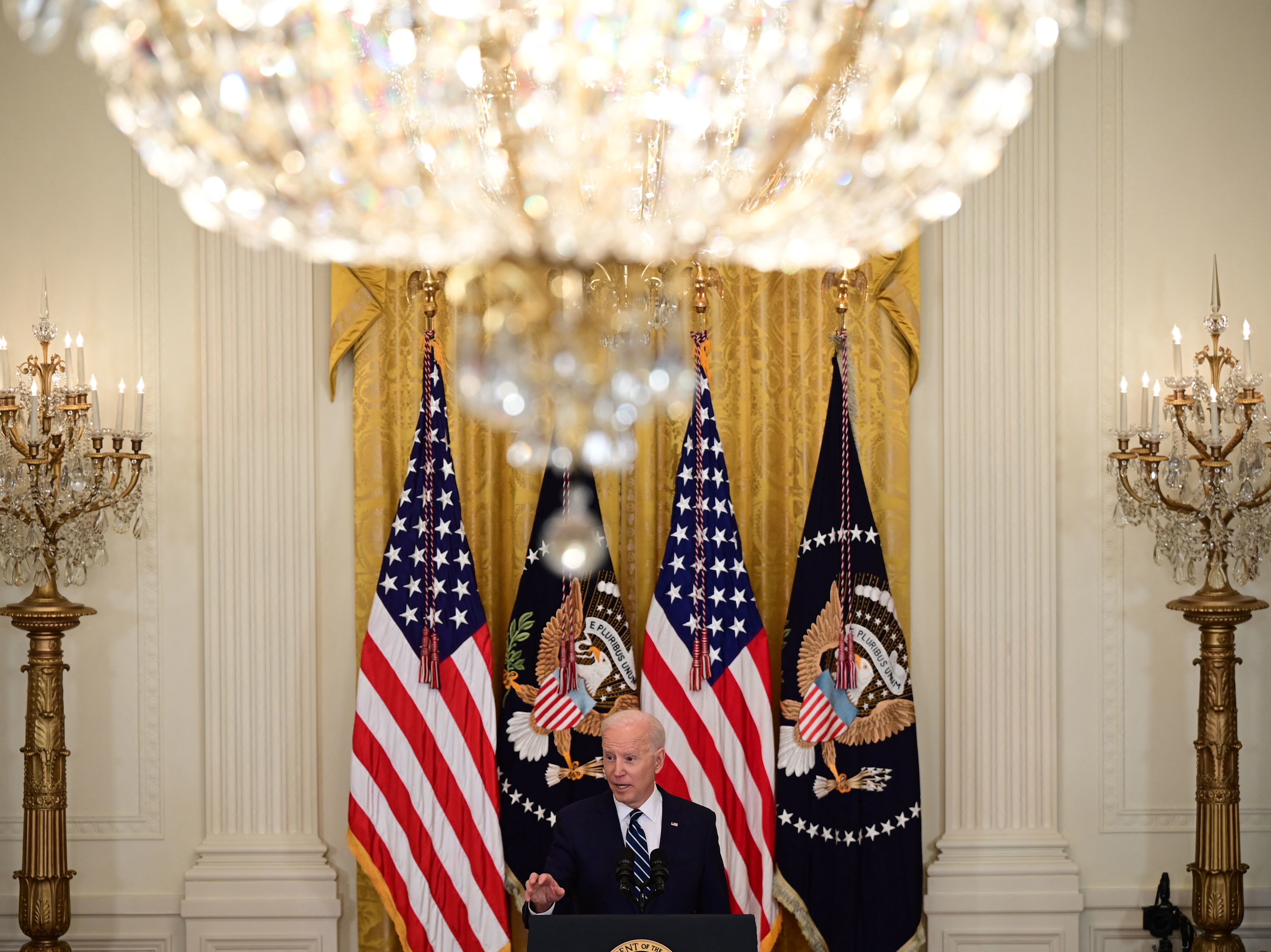caption: President Biden speaks during his first press briefing in the East Room of the White House on Thursday.