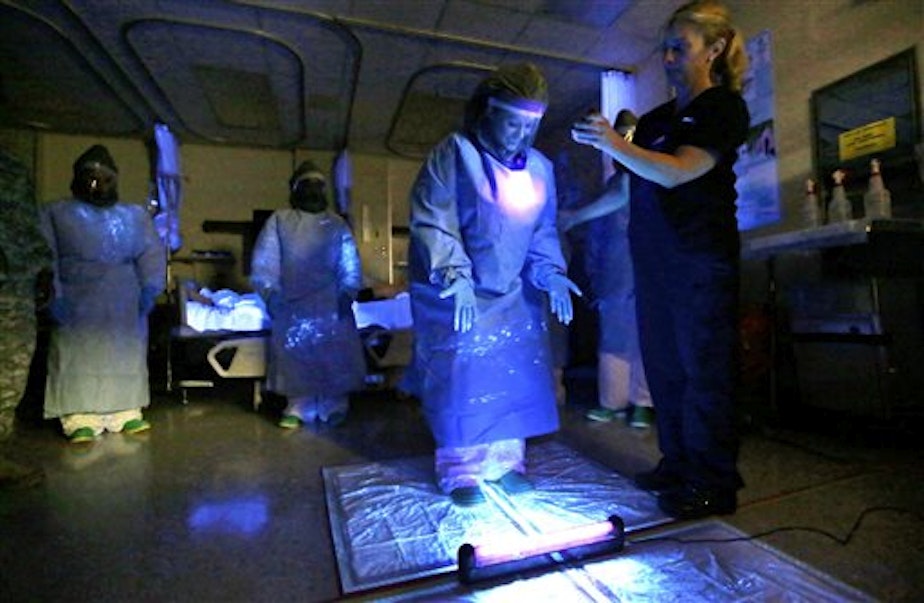 caption: A medical worker, training to treat Ebola patients last week at Madigan Army Medical Center, is illuminated with a black light used to look for traces of fluids which could transmit the Ebola virus.